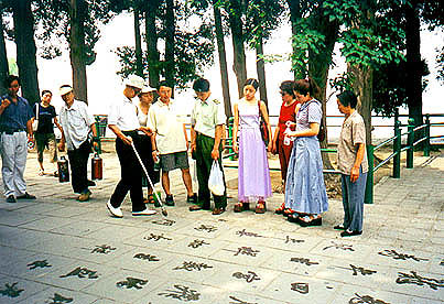 Painting calligraphy on the sidewalk with plain water and a large brush; we think he was writing poetry